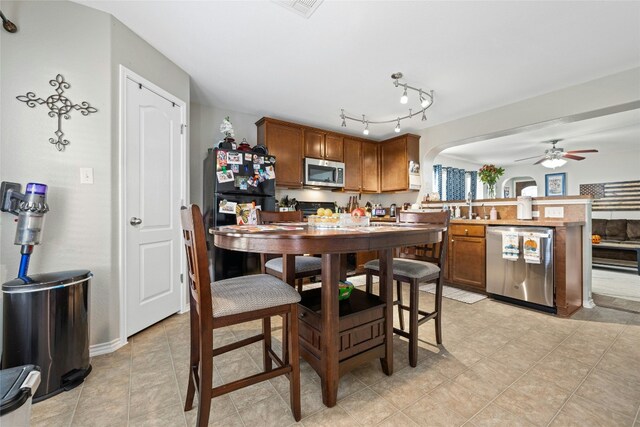 3204 Barksdale Dr, Austin, TX 78725 - kitchen featuring appliances with stainless steel finishes, a peninsula, brown cabinets, a ceiling fan, and arched walkways