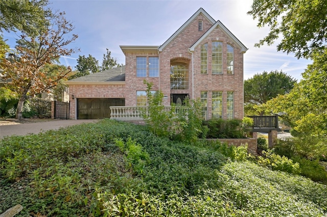 traditional-style home with driveway, brick siding, an attached garage, and fence