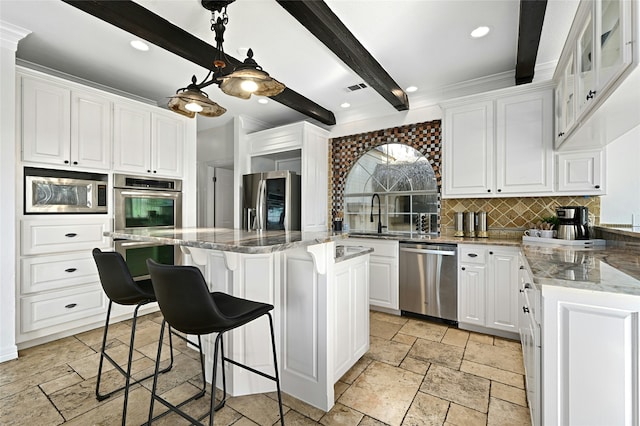 kitchen with beamed ceiling, stone tile flooring, white cabinetry, appliances with stainless steel finishes, and decorative backsplash