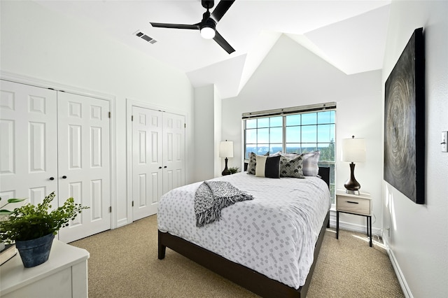 bedroom featuring vaulted ceiling, visible vents, two closets, and light carpet