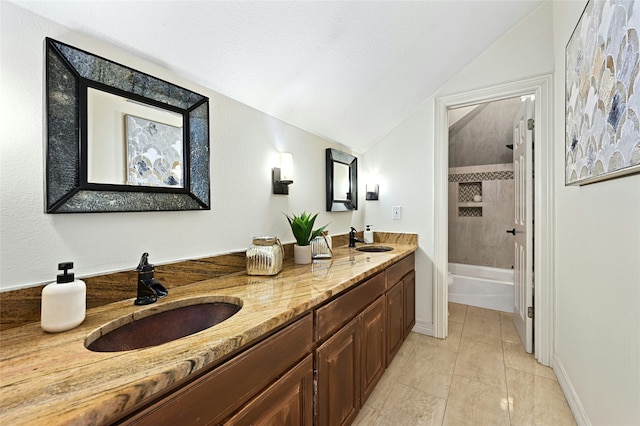 bathroom with tile patterned floors, vanity, tiled shower / bath combo, and lofted ceiling