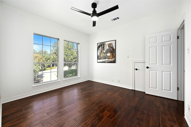 spare room with dark wood finished floors, visible vents, ceiling fan, and baseboards