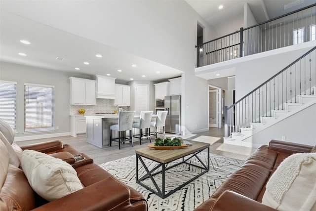 living room featuring a towering ceiling and light hardwood / wood-style flooring