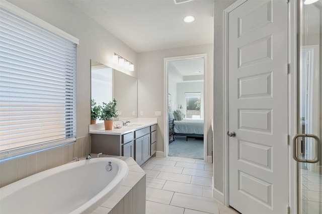 bathroom with tile patterned flooring, vanity, and a relaxing tiled tub