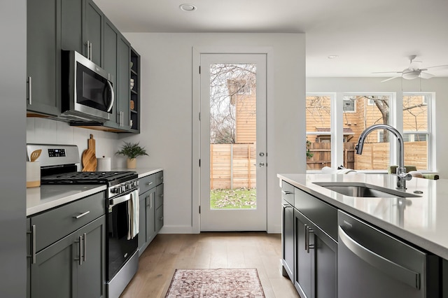 kitchen featuring ceiling fan, appliances with stainless steel finishes, sink, and light hardwood / wood-style floors