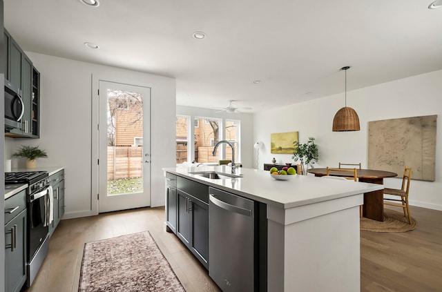 kitchen featuring decorative light fixtures, ceiling fan, sink, a kitchen island with sink, and appliances with stainless steel finishes