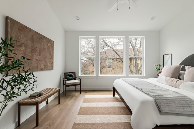 bedroom featuring ceiling fan, multiple windows, light hardwood / wood-style flooring, and vaulted ceiling