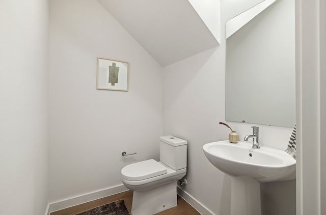 bathroom with toilet, lofted ceiling, wood-type flooring, and sink