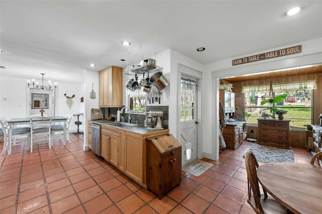 kitchen with backsplash, dark tile patterned flooring, sink, stainless steel dishwasher, and a notable chandelier