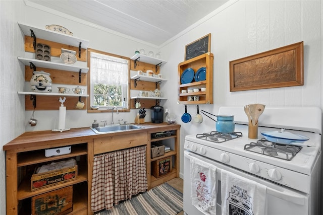 kitchen with wood counters, gas range gas stove, sink, and ornamental molding