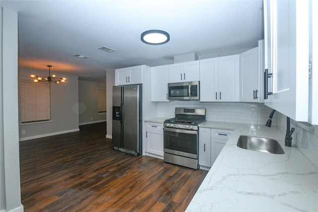 kitchen featuring decorative backsplash, appliances with stainless steel finishes, a notable chandelier, white cabinets, and dark hardwood / wood-style floors