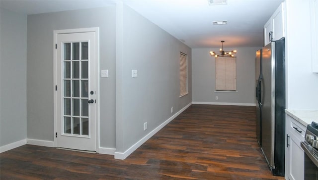 hall featuring dark wood-type flooring and a notable chandelier