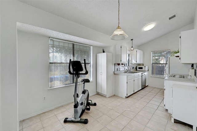 kitchen featuring dishwasher, white cabinetry, hanging light fixtures, and vaulted ceiling