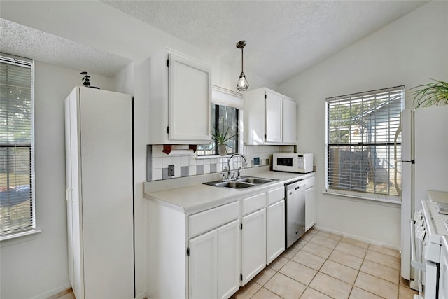 kitchen with white appliances, backsplash, white cabinets, sink, and decorative light fixtures