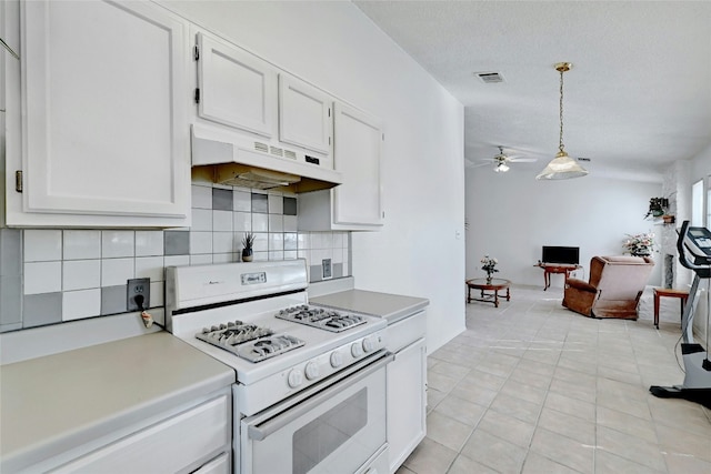 kitchen with tasteful backsplash, white range, light tile patterned floors, decorative light fixtures, and white cabinetry