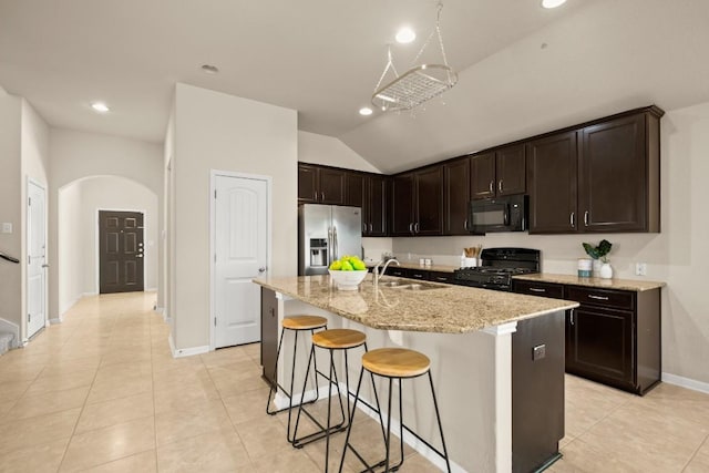 kitchen with sink, vaulted ceiling, a kitchen island with sink, light tile patterned flooring, and black appliances