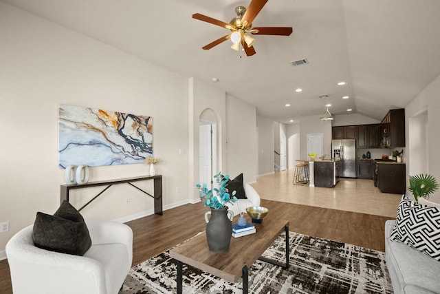 living room with ceiling fan, lofted ceiling, and hardwood / wood-style flooring