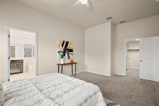 bedroom featuring light colored carpet, ceiling fan, a spacious closet, connected bathroom, and a closet