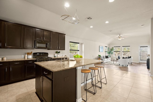 kitchen featuring black appliances, a kitchen island with sink, a wealth of natural light, and vaulted ceiling