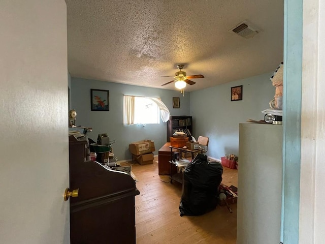 bedroom featuring ceiling fan, light hardwood / wood-style floors, and a textured ceiling