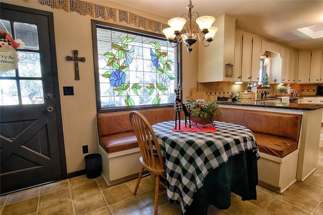 dining space with a wealth of natural light, sink, light tile patterned floors, and a chandelier