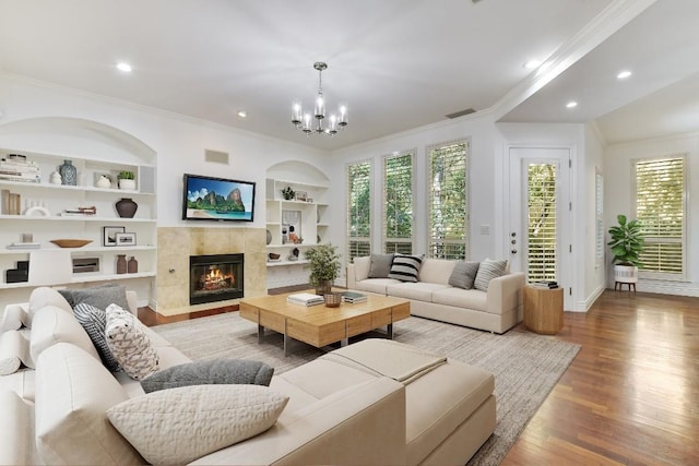 living room featuring ornamental molding, wood-type flooring, a tile fireplace, and built in features