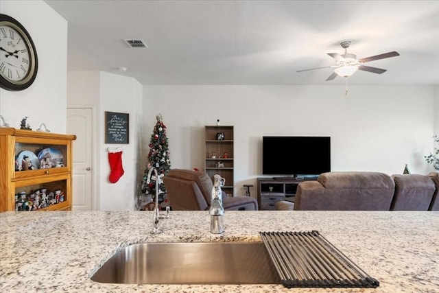 kitchen with sink, light stone countertops, and ceiling fan