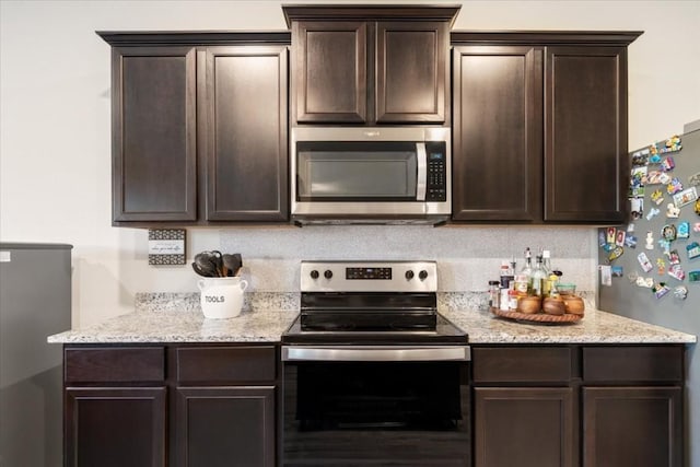 kitchen with stainless steel appliances, light stone countertops, dark brown cabinets, and backsplash