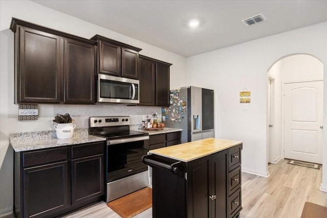 kitchen featuring appliances with stainless steel finishes, dark brown cabinets, and light hardwood / wood-style flooring