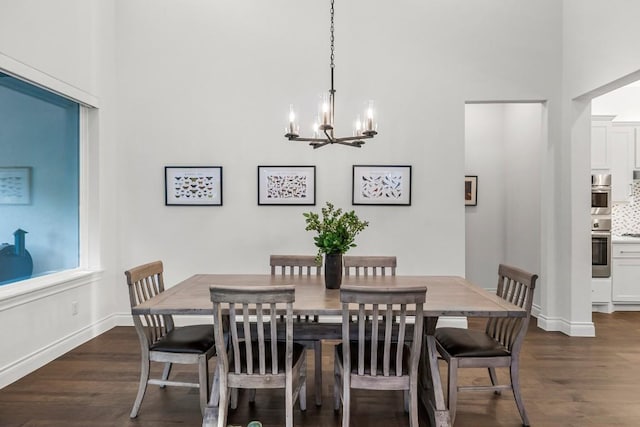 dining space featuring dark wood-type flooring, a chandelier, and a high ceiling