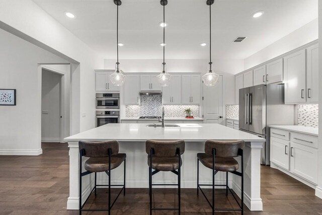 kitchen featuring a kitchen island with sink, dark hardwood / wood-style flooring, and decorative light fixtures