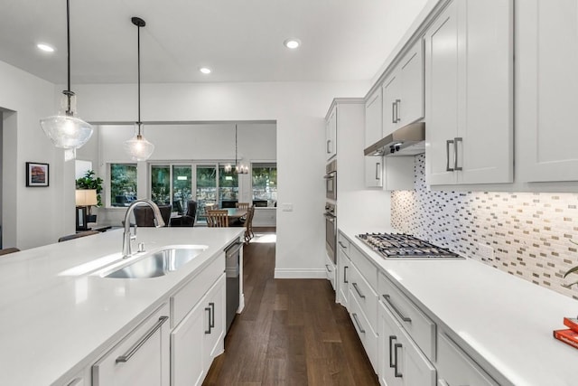 kitchen with stainless steel appliances, sink, white cabinets, dark hardwood / wood-style floors, and hanging light fixtures