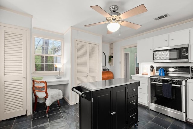 kitchen featuring ornamental molding, stainless steel appliances, ceiling fan, a center island, and white cabinetry