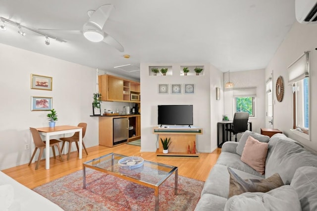 living room with ceiling fan, a wall mounted air conditioner, and light wood-type flooring