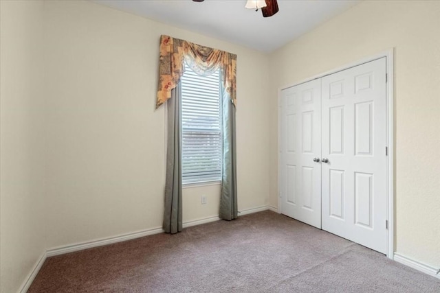 unfurnished bedroom featuring light carpet, ceiling fan, baseboards, and a closet