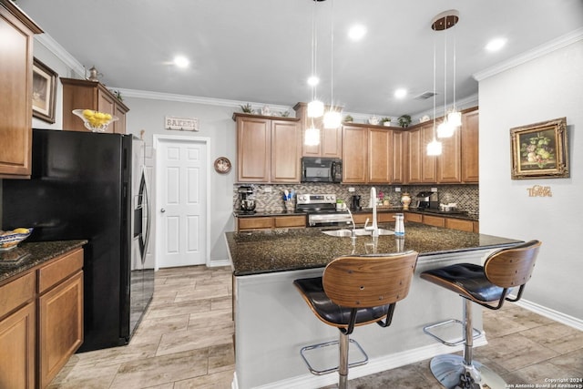 kitchen featuring a kitchen island with sink, a sink, decorative light fixtures, and black appliances