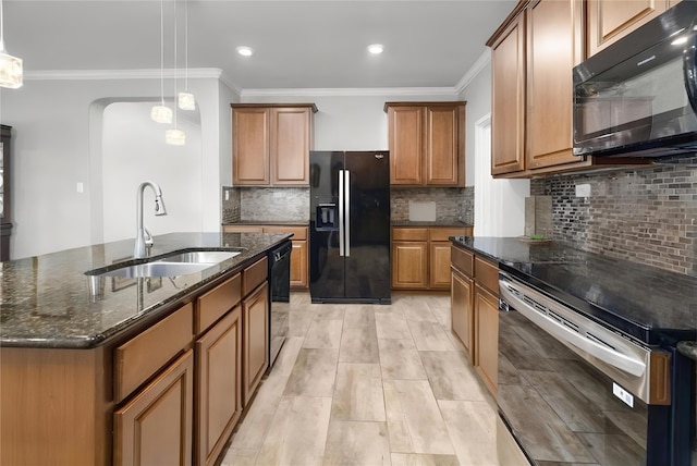 kitchen featuring decorative light fixtures, a center island with sink, brown cabinetry, a sink, and black appliances