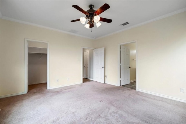 unfurnished bedroom featuring crown molding, a walk in closet, visible vents, and baseboards