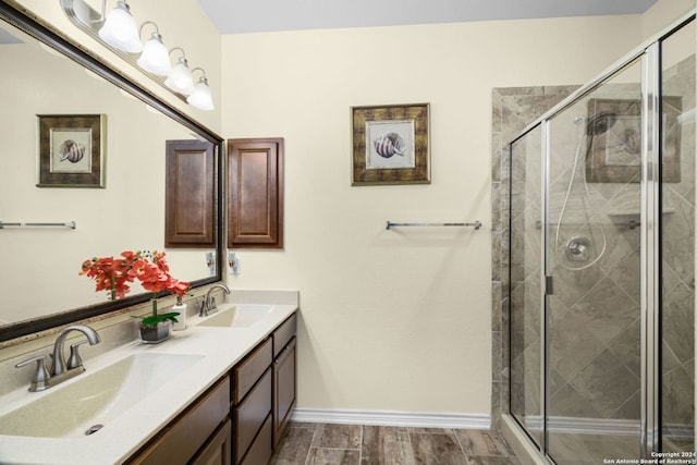 bathroom with a stall shower, a sink, and wood finished floors