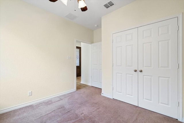 unfurnished bedroom featuring baseboards, visible vents, a ceiling fan, light colored carpet, and a closet