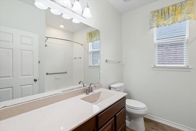 bathroom featuring toilet, vanity, wood finished floors, baseboards, and walk in shower