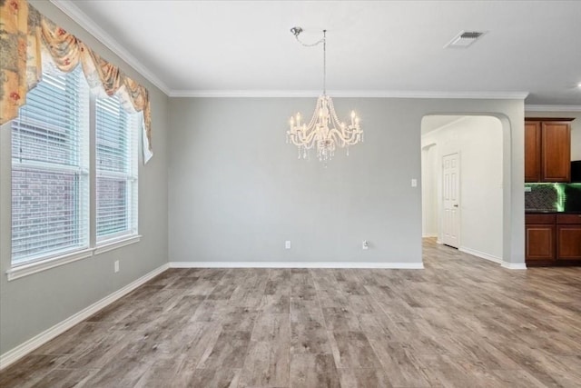 unfurnished dining area with arched walkways, visible vents, crown molding, and wood finished floors