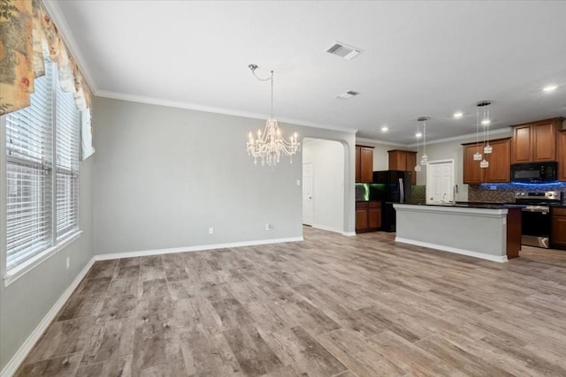 kitchen featuring dark countertops, pendant lighting, open floor plan, and black appliances