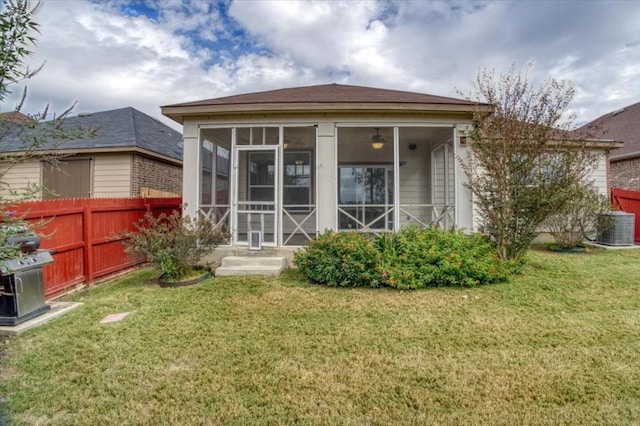 back of property with a sunroom, fence, and a yard