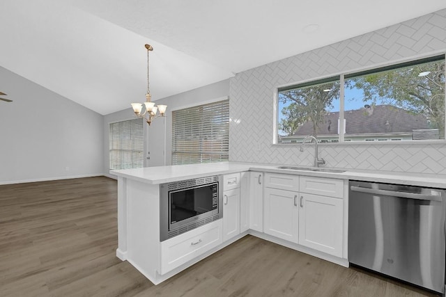 kitchen featuring stainless steel appliances, vaulted ceiling, sink, hardwood / wood-style flooring, and white cabinetry