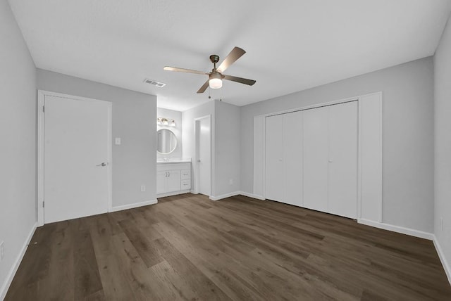 unfurnished bedroom featuring ceiling fan, a closet, dark hardwood / wood-style flooring, and ensuite bath