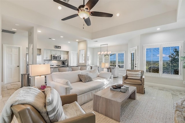 living room featuring sink and ceiling fan with notable chandelier