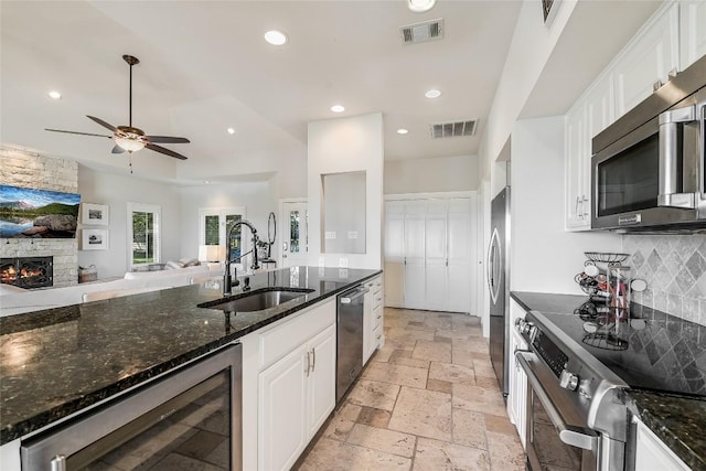 kitchen featuring white cabinets, appliances with stainless steel finishes, beverage cooler, and sink