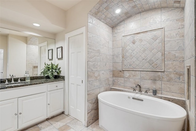 bathroom with vanity, a tub to relax in, and tile walls