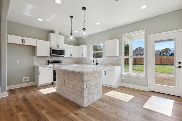 kitchen featuring a center island, light hardwood / wood-style flooring, tasteful backsplash, white cabinetry, and stainless steel appliances